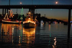 boats decorated with lights pass underneath a bridge